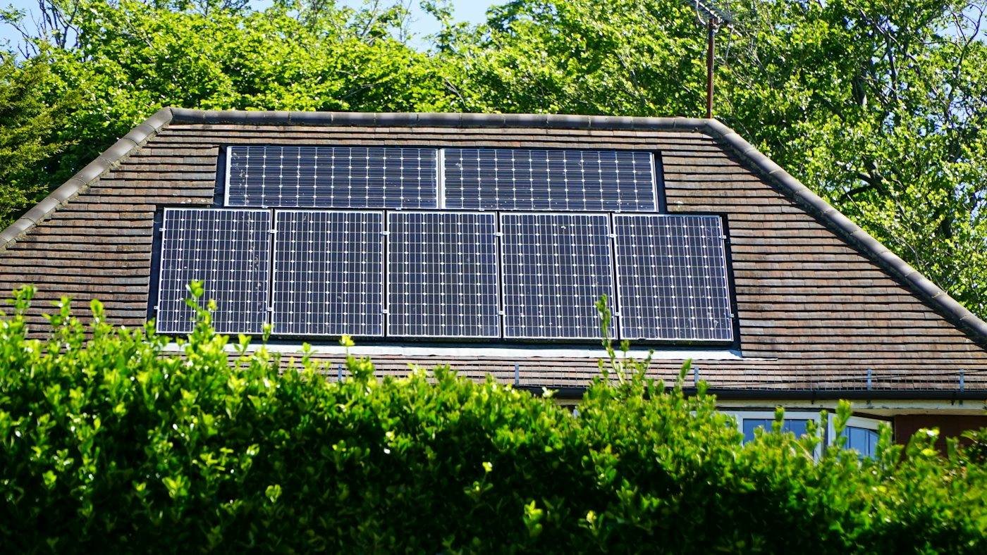 Solar panels on the roof of a house surrounded by greenery